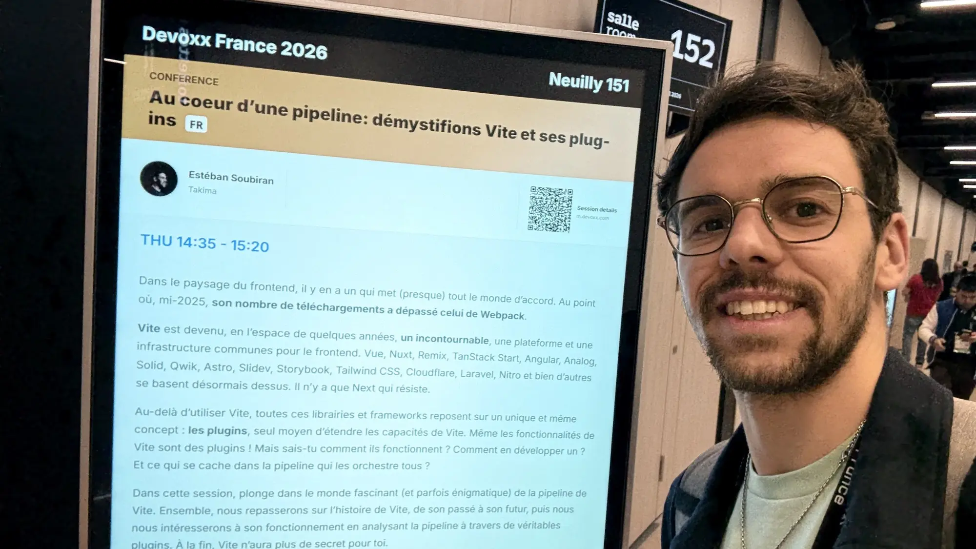 Estéban, in front of the announcement panel, before the talk starts